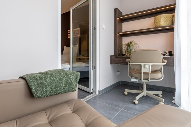Wintergarten mit Büro und gemütlicher Sitzecke im möblierten Micro Apartment und Blick ins Zimmer